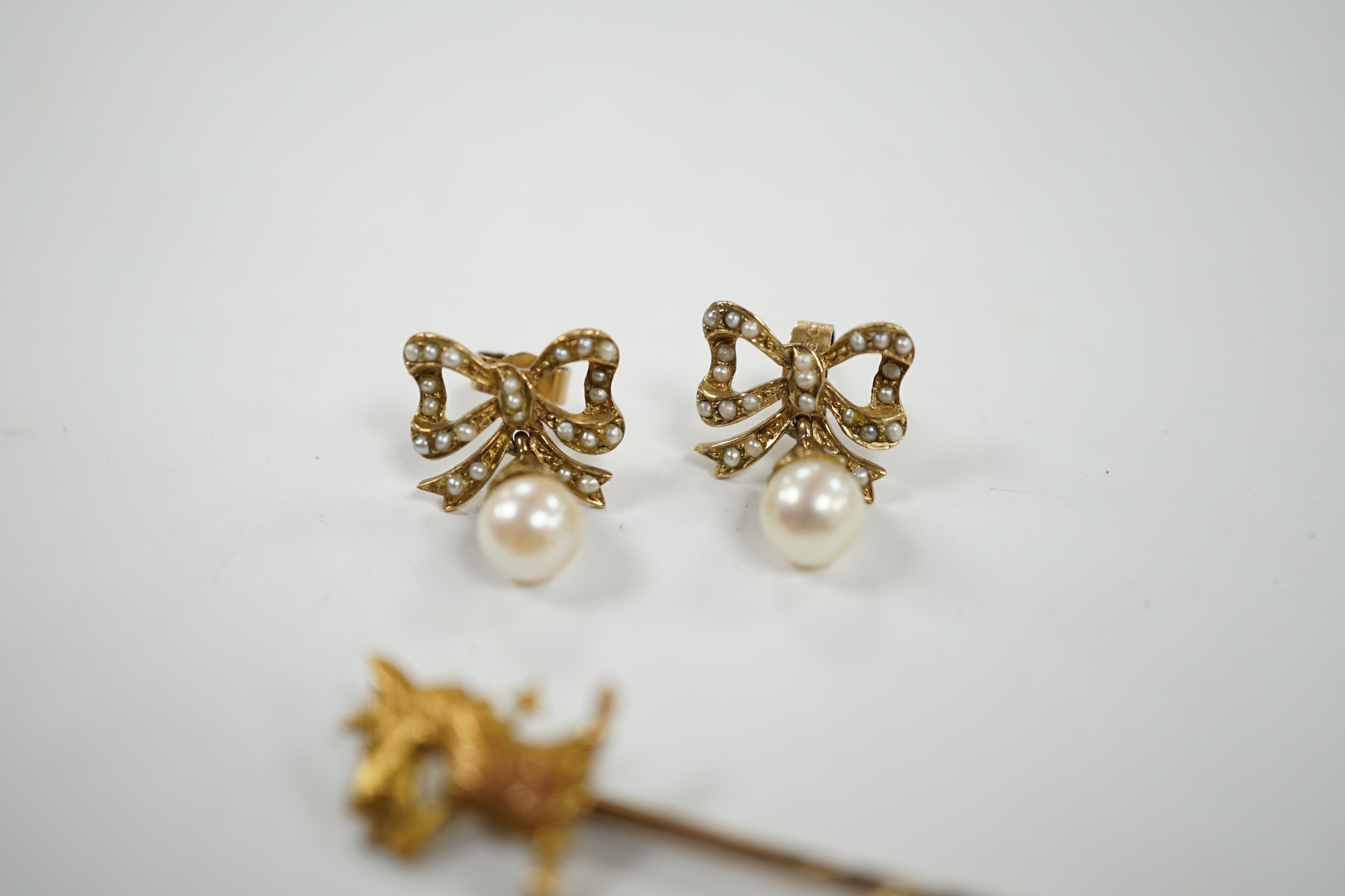 A pair of 9ct, single stone cultured pearl and seed pearl cluster set 'ribbon bow' drop ear studs, 17mm, together with a yellow metal 'armorial' stick pin. Condition - fair to good